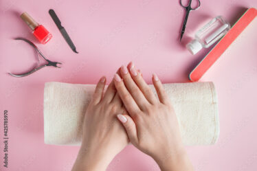 Spa procedure for nail care in a beauty salon. Female hands and tools for manicure on pink background. Bodycare concept.